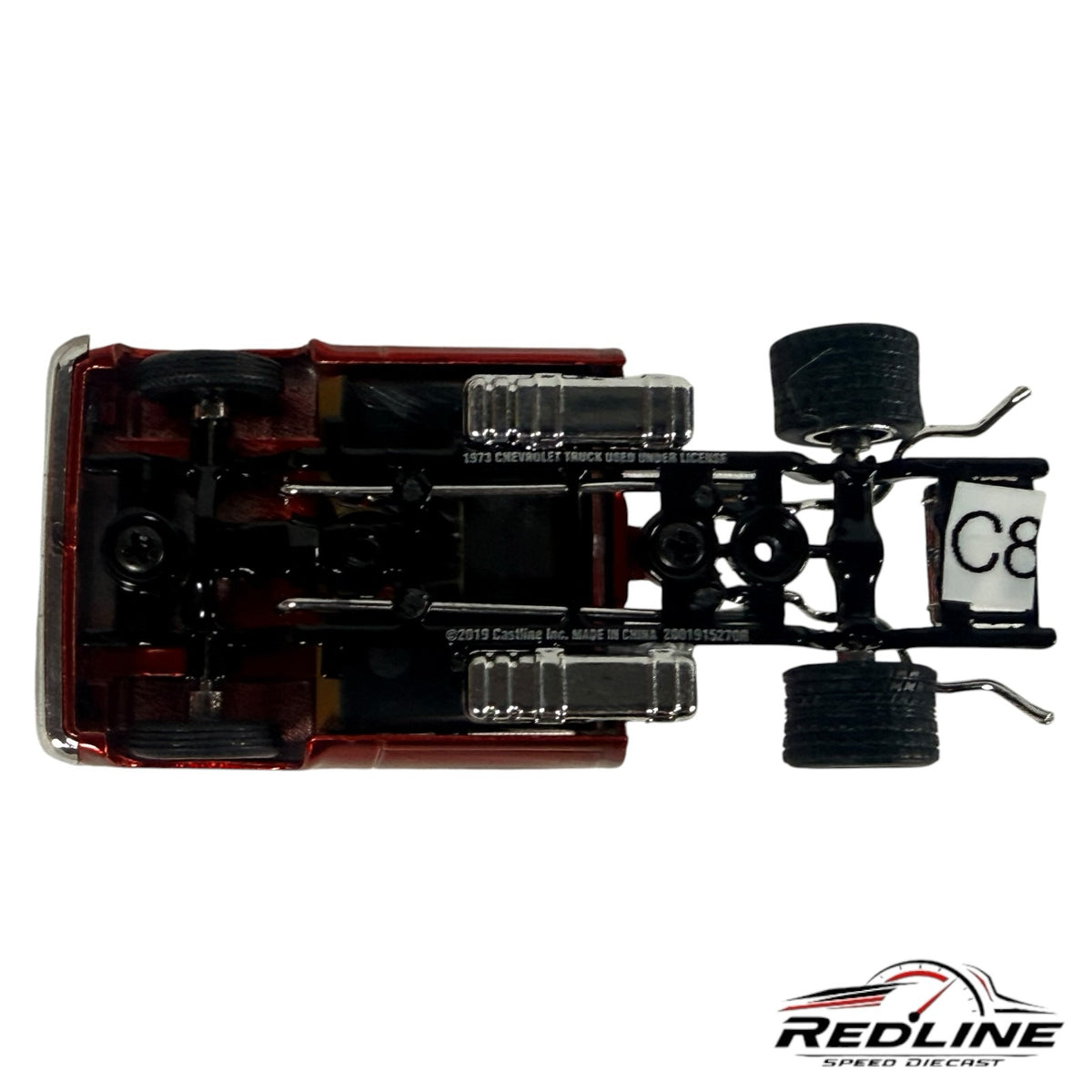 Underside view of a Redline Speed Diecast 1973 Chevrolet Cheyenne model showing the chassis, exhaust, and rear tires.