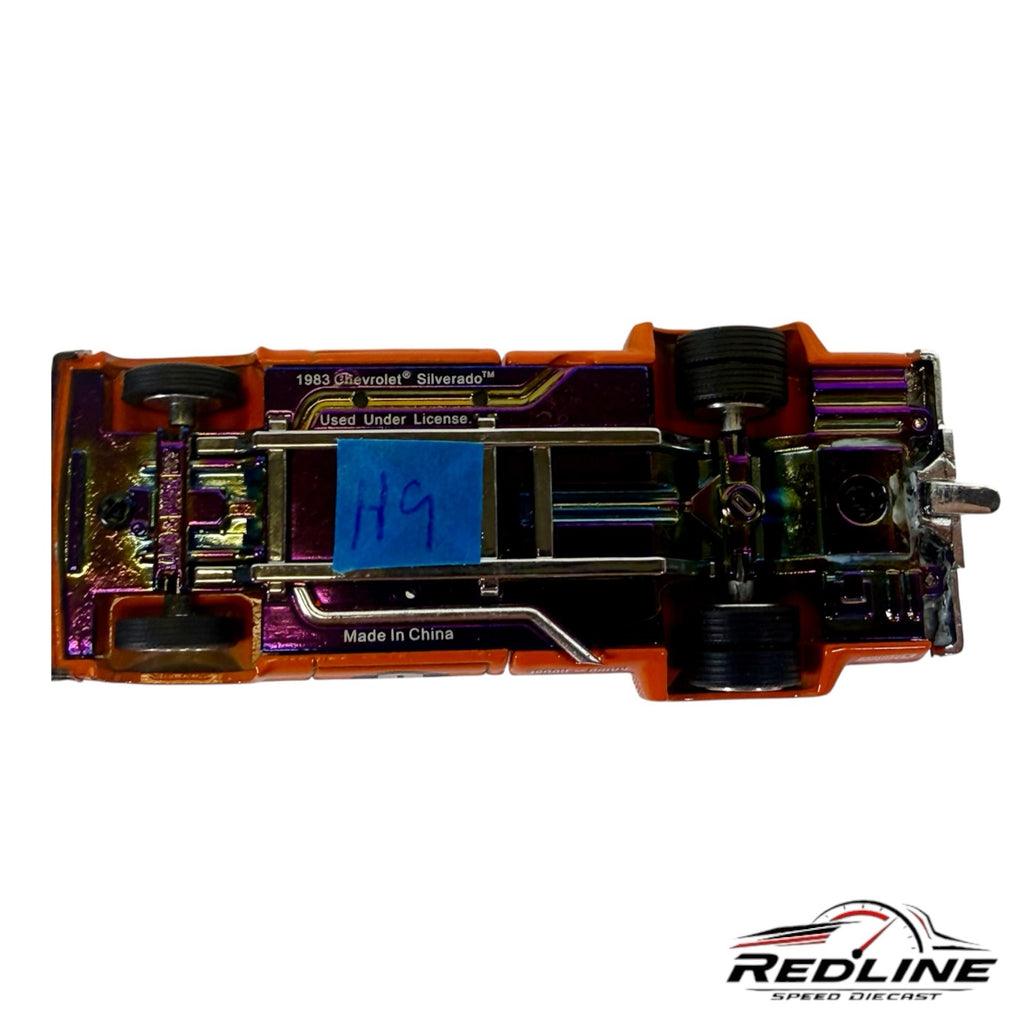 Underside view of Redline Speed Diecast 1983 Chevrolet Silverado featuring an iridescent chassis and orange body