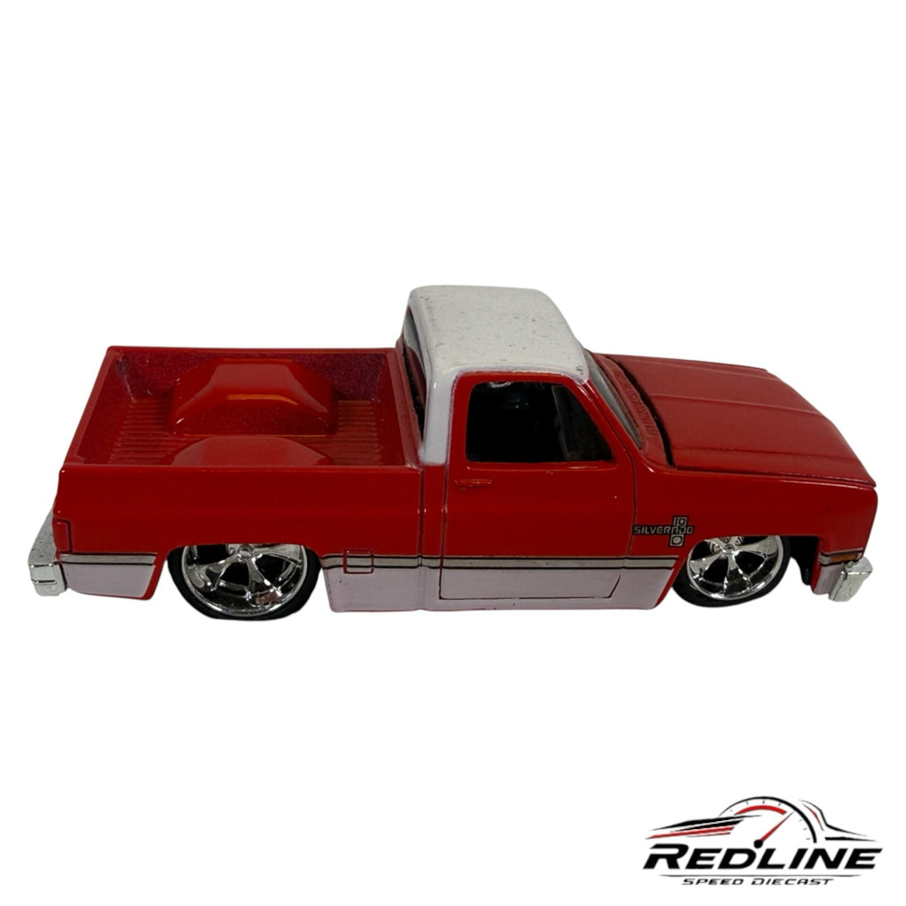 Redline Speed Diecast 1987 Chevrolet Silverado truck model in red and white with chrome wheels and lowered stance