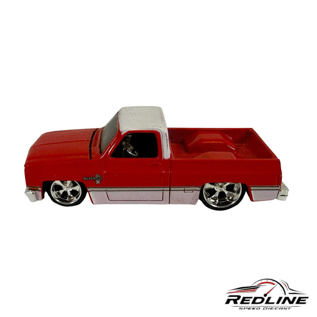 Redline Speed Diecast 1987 Chevrolet Silverado model truck in red and white with chrome wheels and detailed bed.
