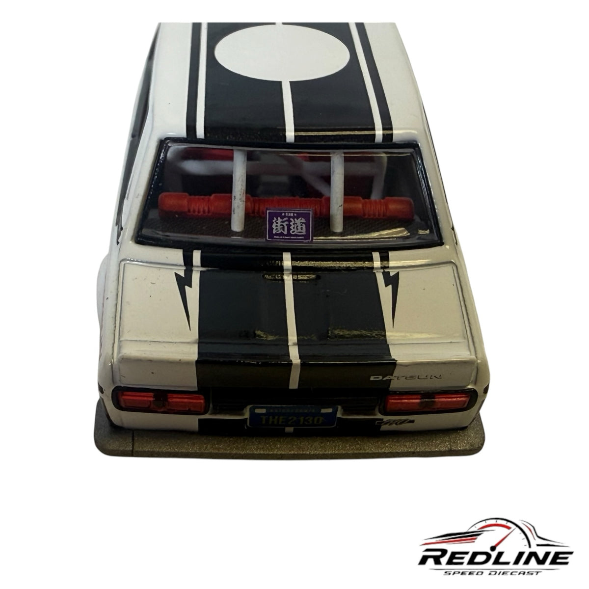 Redline Speed Diecast Datsun 510 model car rear view featuring white paint, black racing stripes, and red interior
