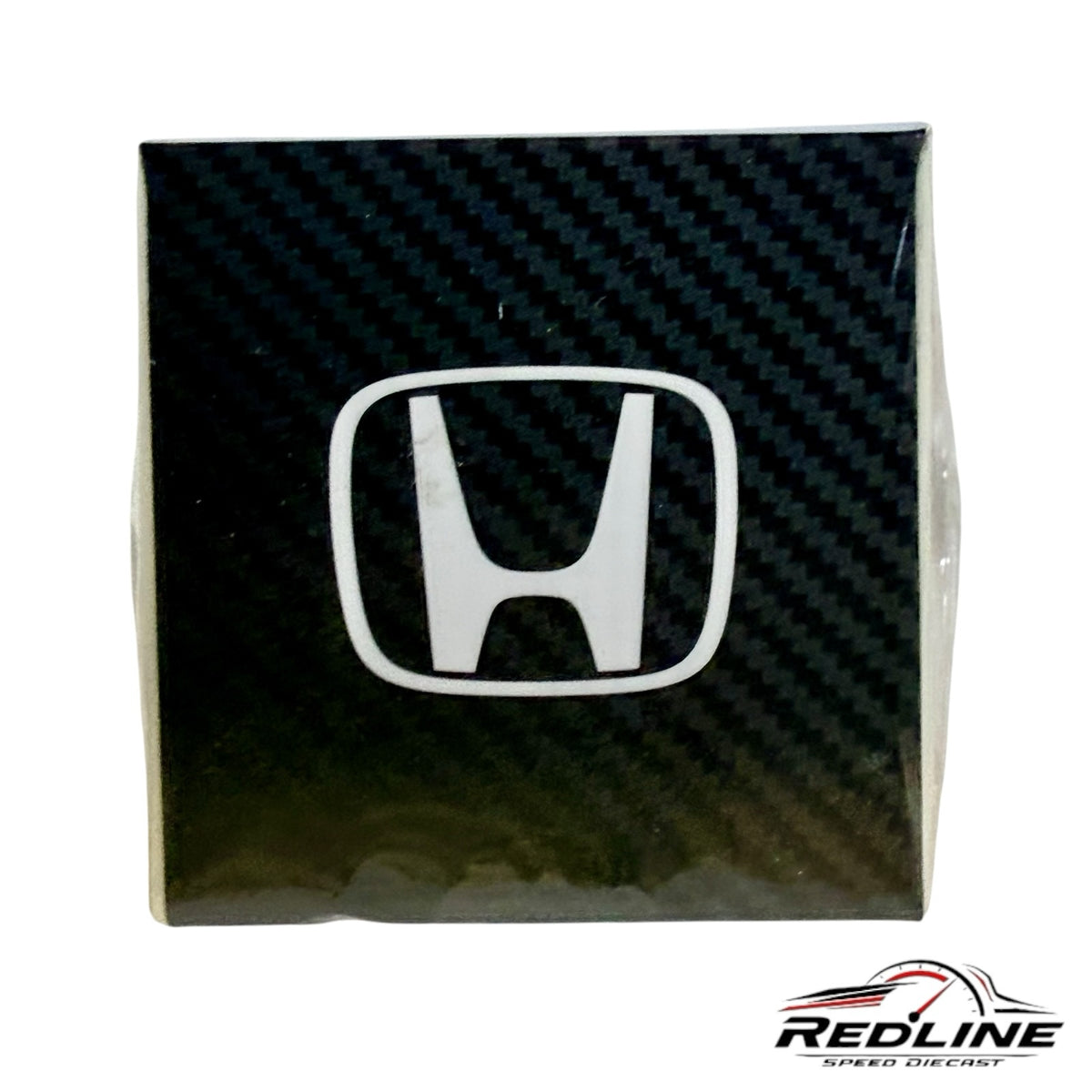 Redline Speed Diecast Honda logo emblem on a black carbon fiber textured background for Kaido House model packaging
