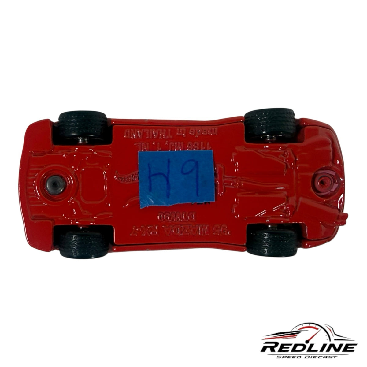 Underside view of a Redline Speed Diecast 1995 Mazda RX-7 model car showing red chassis and black wheels