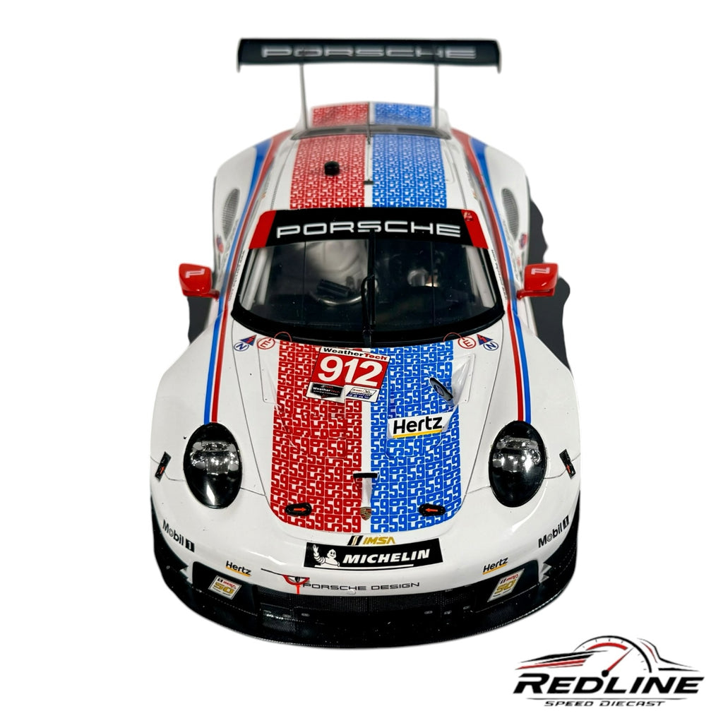 Redline Speed Diecast 1:18 scale Porsche 911 RSR race car model with white, red, and blue livery on display base.